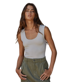 Woman wearing a white tank top and green pants on a white background