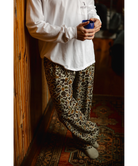 Person wearing a camo print pajama pants holding a blue coffee cup indoors.