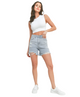 A woman posing in cutoff denim shorts with a high waist and distressed details, paired with a white sleeveless top.