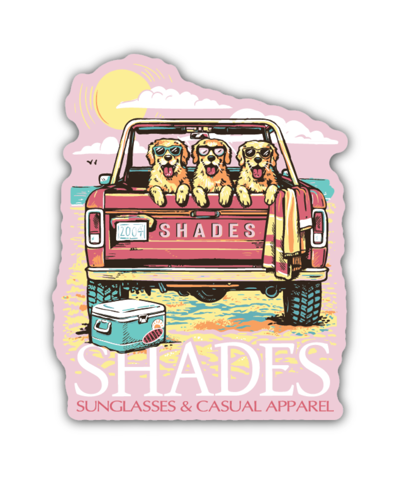 A die-cut sticker featuring a retro-style illustration of three golden retriever dogs wearing sunglasses in the bed of a pink pickup truck on a beach. The sticker includes the text 'SHADES' and 'SUNGLASSES & CASUAL APPAREL' on a white background.