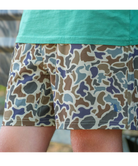 Close-up of a person wearing camouflage shorts with a turquoise shirt, photographed outdoors.