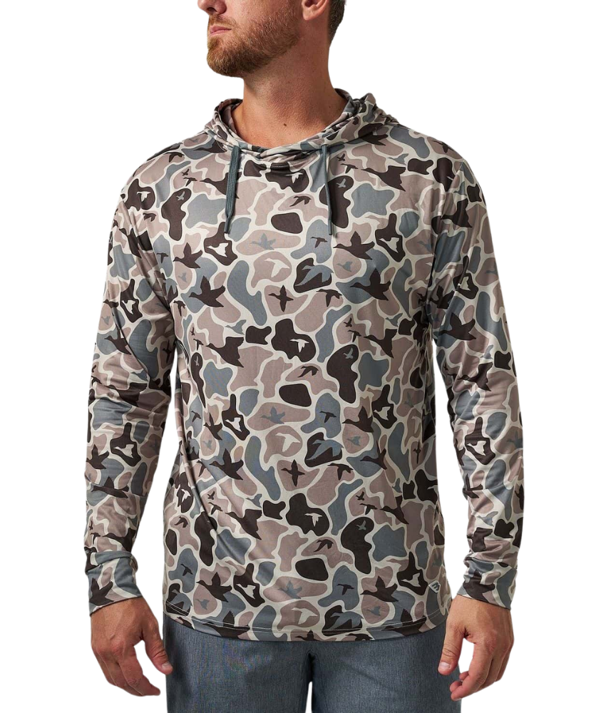 A man wearing a long-sleeve camouflage hoodie in shades of gray, beige, and black, paired with blue jeans, shown from the waist up against a plain white background.
