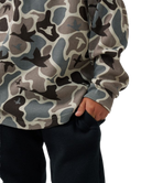Close-up of a child wearing a waffle-knit long-sleeve sweatshirt with a muted camouflage pattern in gray, beige, brown, and black, paired with dark pants, against a white background.