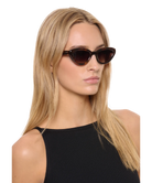 Woman wearing cat-eye Krewe sunglasses with a plain background