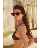 Woman wearing cat-eye Krewe sunglasses with a plain background