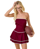 Woman in a maroon dress holding a football on a white background