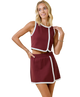 Woman wearing a maroon outfit with white trim on a white background