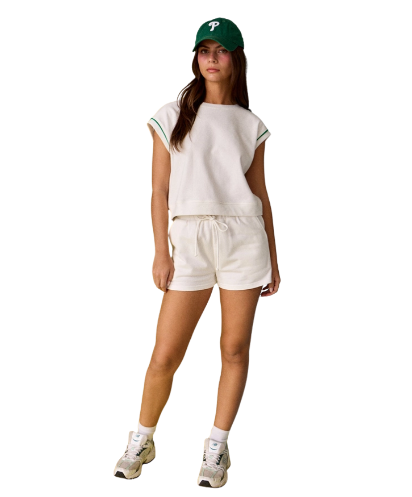 Woman wearing a white outfit with a green cap on a white background