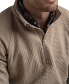 Man wearing a light brown long-sleeve quarter-zip pullover on a white background