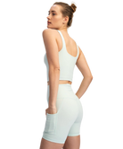 Woman wearing a light green athletic outfit on a white background