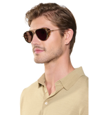 Man wearing a beige shirt and Krewe sunglasses on a white background