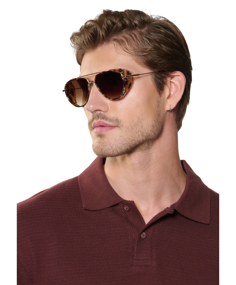 Man wearing brown Krewe sunglasses and a maroon polo shirt on a white background