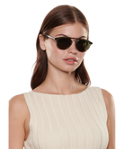 Woman wearing dark Krewe sunglasses on a white background