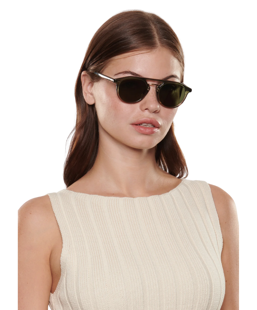 Woman wearing dark Krewe sunglasses on a white background