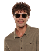 Man wearing Krewe Markle sunglasses and a brown shirt on a white background
