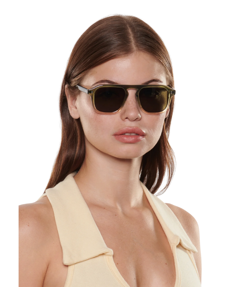 Woman wearing Krewe sunglasses with a plain background