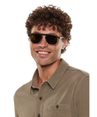 Man wearing Krewe sunglasses and a green shirt on a white background