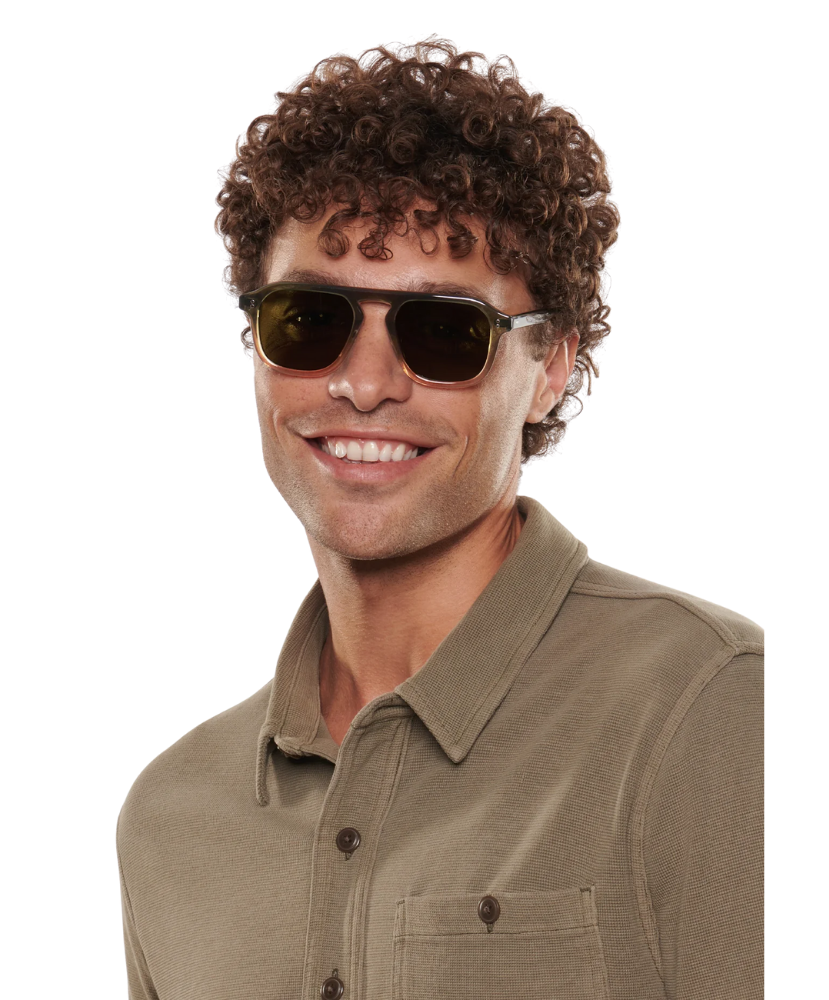 Man wearing Krewe sunglasses and a green shirt on a white background