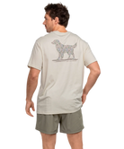 Man wearing a IVORY t-shirt with a CAMO dog graphic on the back, standing against a white background