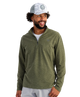 Man wearing a green HUK pullover and white cap on a white background