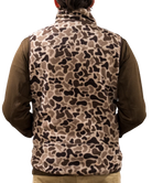 Person wearing a camouflage vest over a brown shirt on a white background