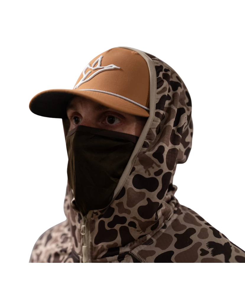 Person wearing a camouflage hooded jacket and brown cap on a white background