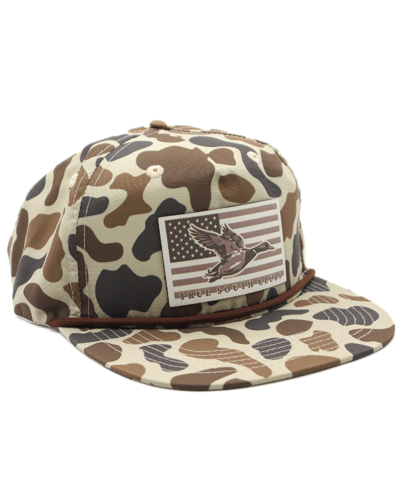 Camouflage-patterned cap with an American flag and mallard duck patch on a white background