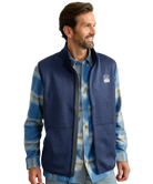 Man wearing a blue fleece vest over a plaid shirt on a white background HUK GEAR VEST