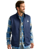Man wearing a blue fleece vest over a plaid shirt on a white background HUK GEAR VEST