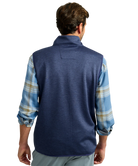 Man wearing a blue fleece vest over a plaid shirt on a white background HUK GEAR VEST
