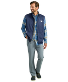 Man wearing a blue fleece vest over a plaid shirt on a white background HUK GEAR VEST