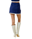 Person wearing a blue skirt and white high-heeled boots on a white background