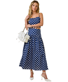 Woman wearing a blue polka dot dress with a white handbag on a white background