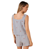 Woman wearing a light blue sleeveless top and shorts with small USA flag patterns on a white background