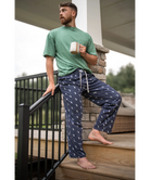 Man navy pajama pants holding a mug on a deck.