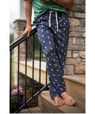 Person wearing navy blue pajama pants with a dog pattern, standing on a staircase.