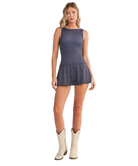 Woman wearing a navy dress with white polka dots on a white background