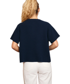 Woman wearing a navy blue sweater and white pants on a white background