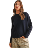 Woman wearing a navy sweater and plaid pants on a white background