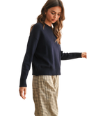 Woman wearing a navy sweater and plaid pants on a white background