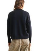 Person wearing a navy sweater and plaid pants on a white background
