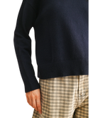 Navy sweater worn by a person with plaid pants on a white background