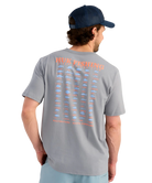 Man wearing a gray t-shirt with fishing-themed design on the back, standing against a white background.