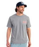 Man wearing a gray t-shirt with branding and a navy cap on a white background