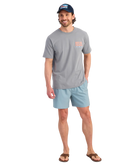 Man wearing a gray t-shirt and light blue shorts on a white background