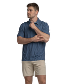 Man wearing a blue golf cart patterned polo shirt and beige shorts on a white background