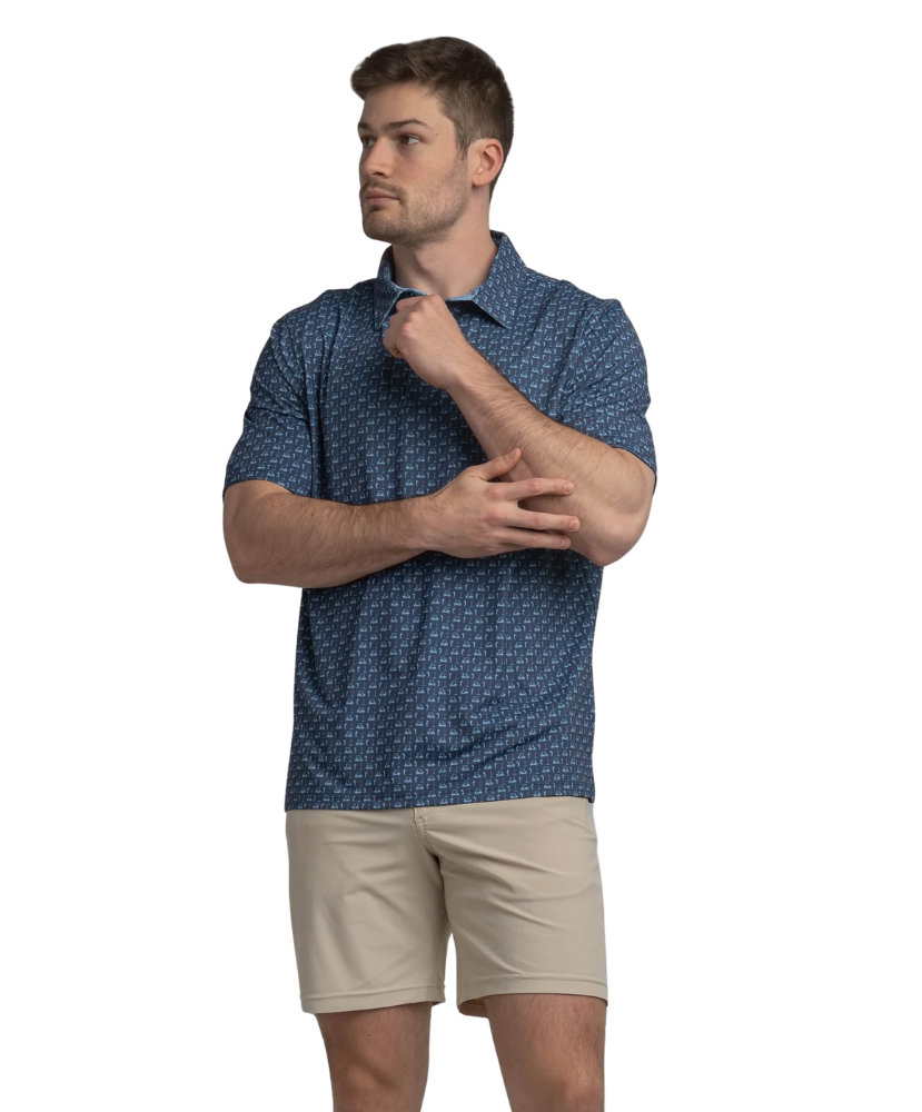 Man wearing a blue golf cart patterned polo shirt and beige shorts on a white background