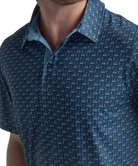 Man wearing a blue golf cart patterned polo shirt and beige shorts on a white background