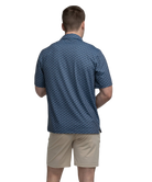 Man wearing a blue golf cart patterned polo shirt and beige shorts on a white background