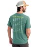Man wearing a green Huk Fishing t-shirt with fish illustrations on the back.